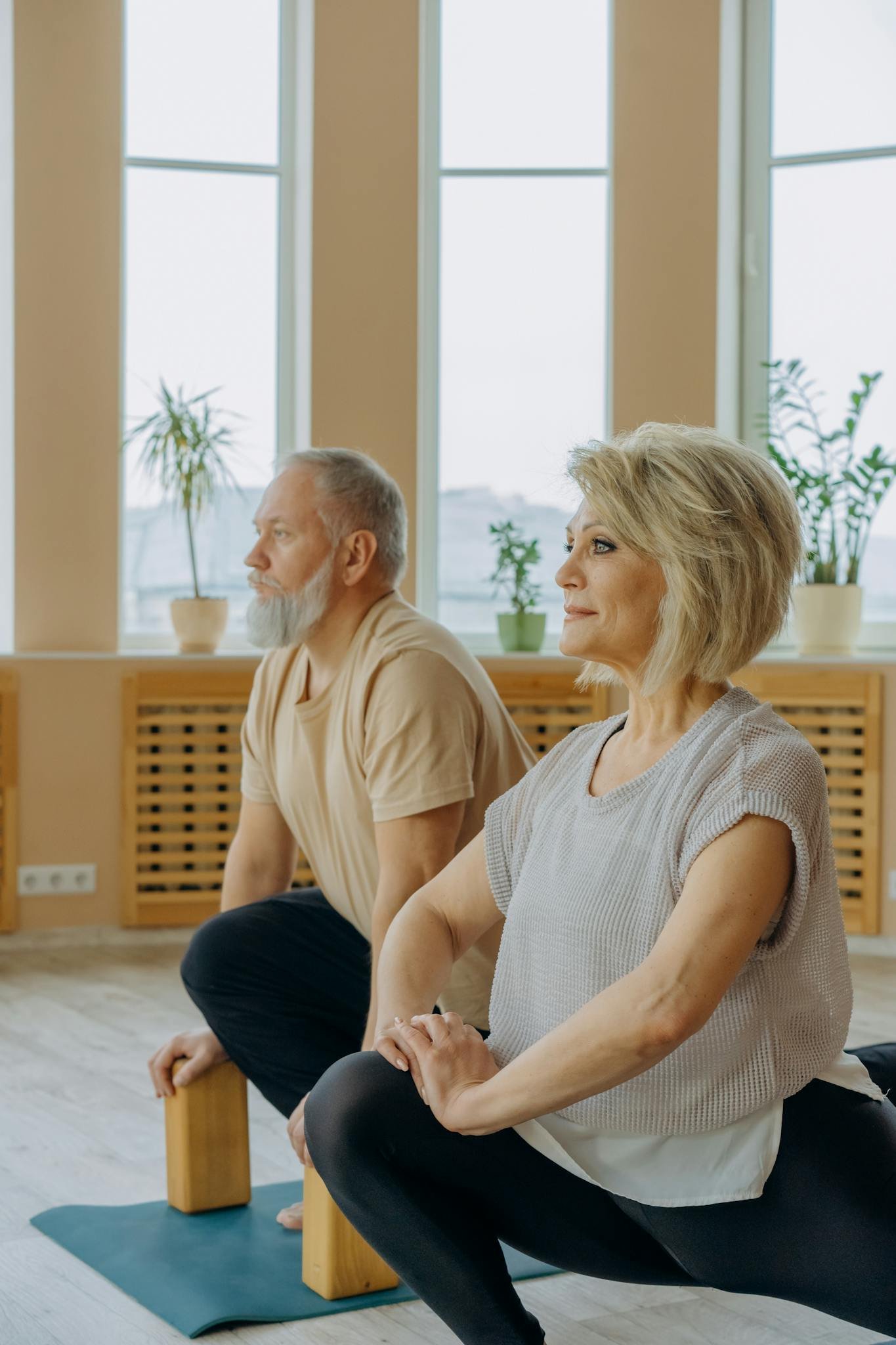 A senior couple practicing yoga indoors, focusing on flexibility and wellbeing.