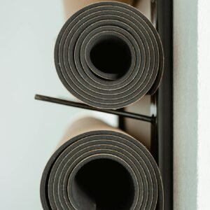 Rolled yoga mats neatly stacked on a rack indoors, ideal for fitness or wellness themes.