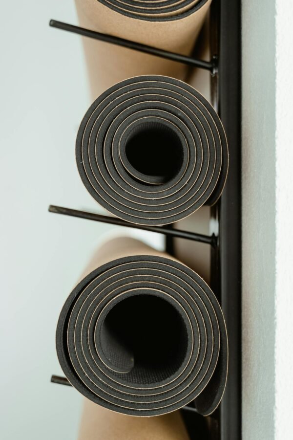 Rolled yoga mats neatly stacked on a rack indoors, ideal for fitness or wellness themes.