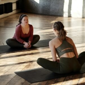 Two women practicing yoga indoors, embracing diversity and wellness.